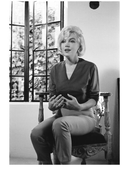 Marilyn Monroe sitzt gestikulierend in einem Sessel vor einem Fenster, Schwarz-Weiß-Fotografie von Allan Grant