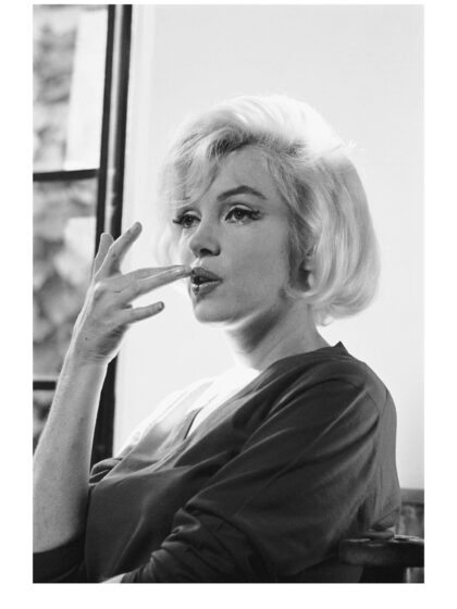 Schwarz-Weiß-Porträt von Marilyn Monroe mit angehobener Hand am Mund und seitlich gerichtetem Blick