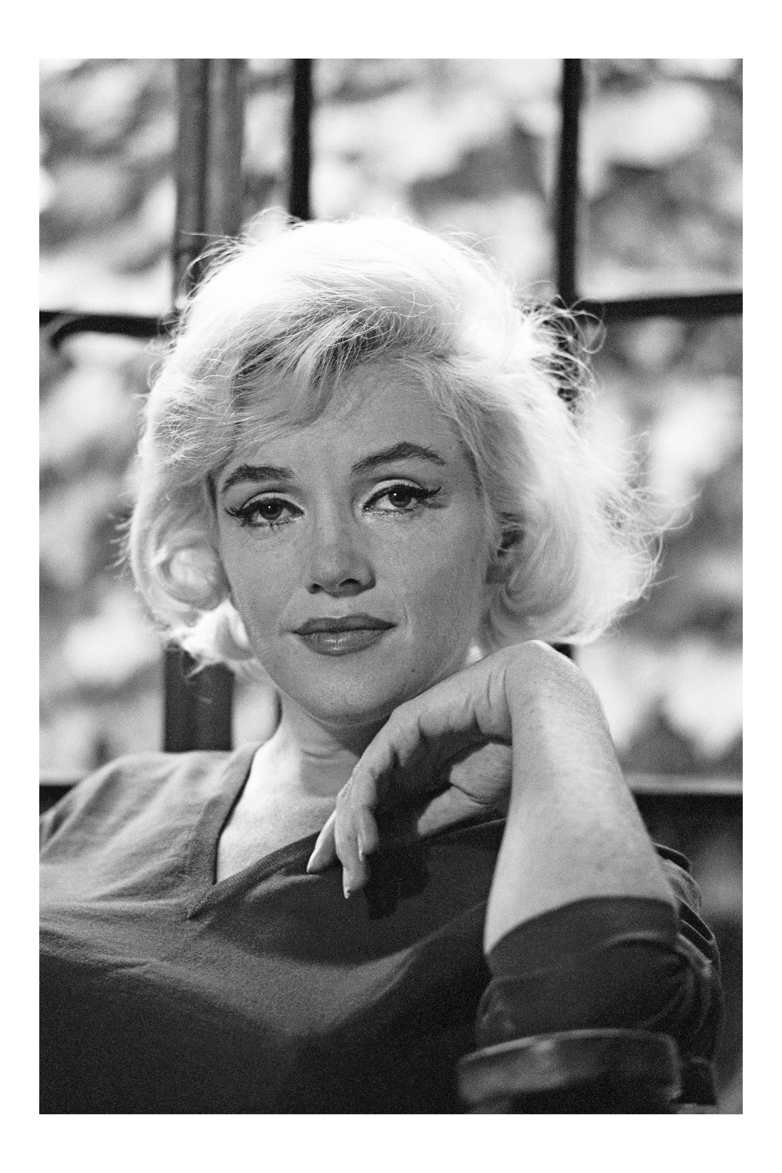 Großformatiges Schwarz-Weiß-Porträt von Marilyn Monroe mit direktem Blick und locker angehobener Hand